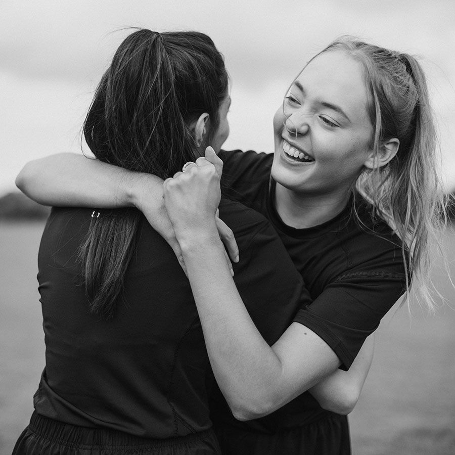 teen girls hugging on a sports field