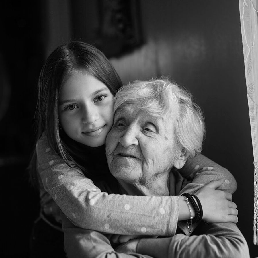 young girl standing behind an older woman and embracing her