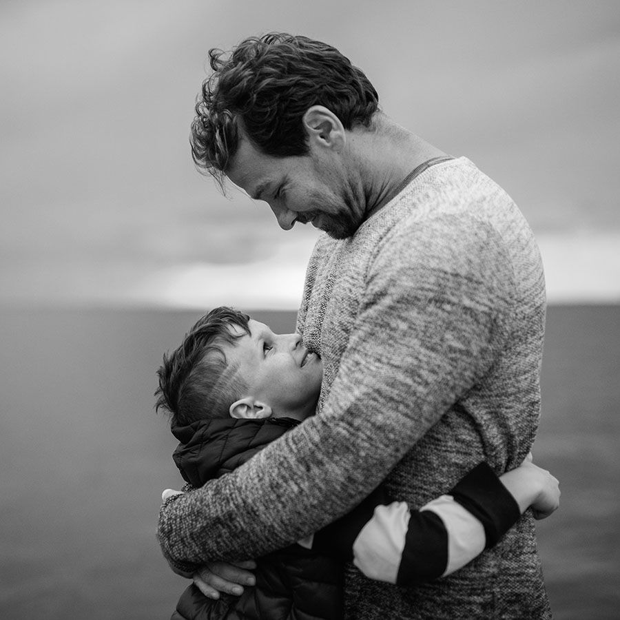 man embracing his young son while on beach