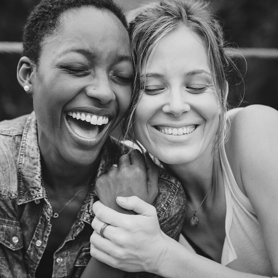 young african american woman and white woman side-hugging with big smiles and eyes closed