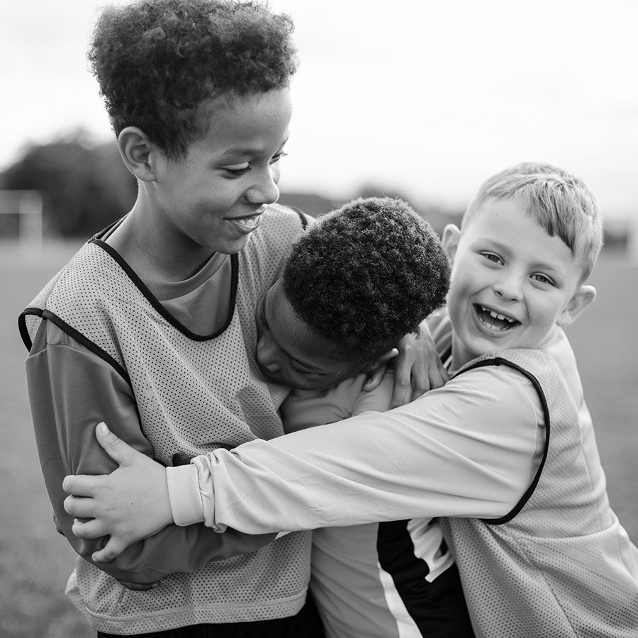 young boys hugging on a sports field